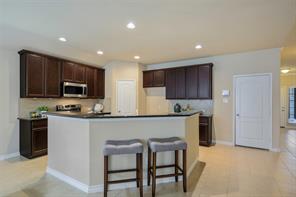 Kitchen featuring tasteful backsplash, dark stone countertops, dark brown cabinetry, light tile floors, and sink