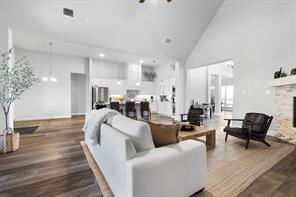 Kitchen has stainless steel appliances, a towering ceiling, and white cabinetry