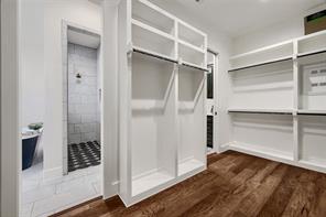 Primary closet boasts custom shelves and wood floors