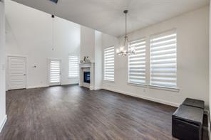 Unfurnished living room featuring a high ceiling, a notable chandelier, dark hardwood / wood-style floors, and a tile fireplace