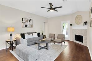 Living room featuring ceiling fan, lofted ceiling, a premium fireplace, and hardwood / wood-style floors