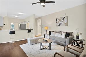 Living room with a fireplace, ceiling fan, and dark wood-type flooring