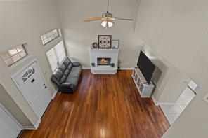 Living room with light hardwood / wood-style floors, a brick fireplace, a textured ceiling, a high ceiling, and ceiling fan