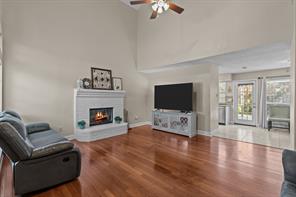 Living room with wood-type flooring, a brick fireplace, and high vaulted ceiling