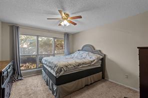 Carpeted bedroom with ceiling fan, a textured ceiling, and a closet