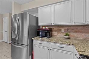 Kitchen featuring decorative backsplash, dishwasher, sink, and white cabinets