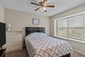 Bedroom featuring a textured ceiling, ceiling fan, and light colored carpet