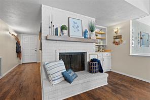 Living room with a brick fireplace, lofted ceiling, ceiling fan, dark hardwood / wood-style floors, and sink