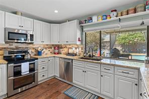 Kitchen featuring pendant lighting, sink, kitchen peninsula, stainless steel appliances, and dark hardwood / wood-style flooring