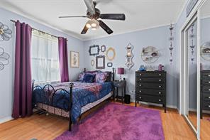 Bedroom with ornamental molding, wood-type flooring, and ceiling fan