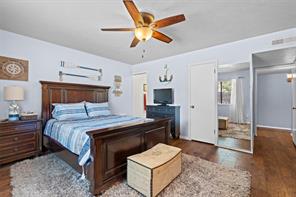 Bedroom featuring ensuite bath, ceiling fan, and dark hardwood / wood-style floors