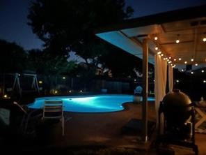 Pool at night with a patio area