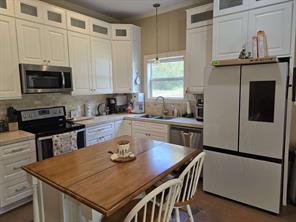 Kitchen with sink, white cabinetry, hanging light fixtures, a kitchen island, and stainless steel appliances