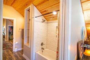 Bedroom featuring ceiling fan, hardwood / wood-style flooring, lofted ceiling, and ensuite bathroom