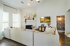 Living room with high vaulted ceiling, ceiling fan, a fireplace, and dark hardwood / wood-style flooring