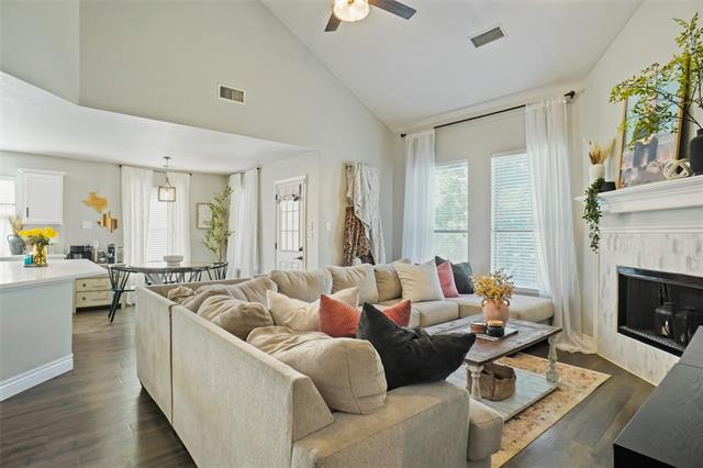 Living room with a towering ceiling, a premium fireplace, ceiling fan, and dark hardwood / wood-style flooring