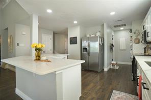 Kitchen with appliances with stainless steel finishes, a kitchen breakfast bar, white cabinets, dark hardwood / wood-style flooring, and decorative light fixtures