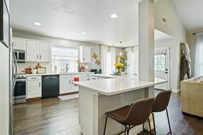 Kitchen featuring tasteful backsplash, dark wood-type flooring, sink, white cabinets, and appliances with stainless steel finishes