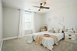 Carpeted bedroom with vaulted ceiling, ceiling fan, and multiple windows