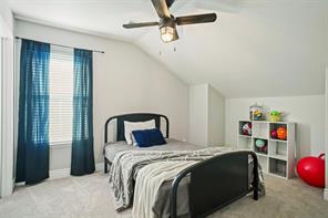 Rec room featuring lofted ceiling, ceiling fan, and light colored carpet